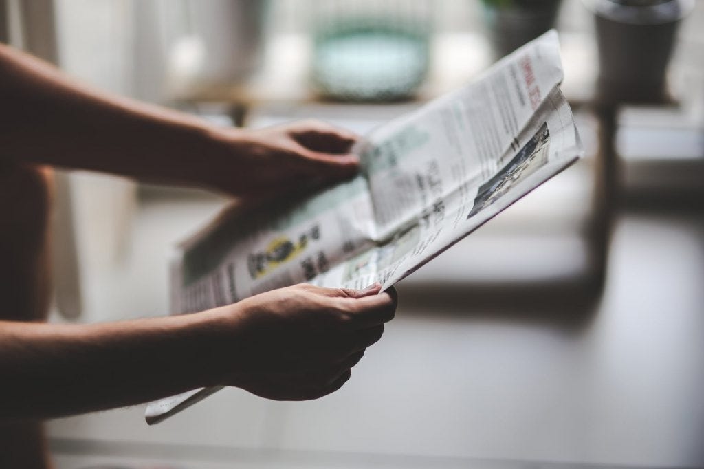 A person holding up a newspaper 