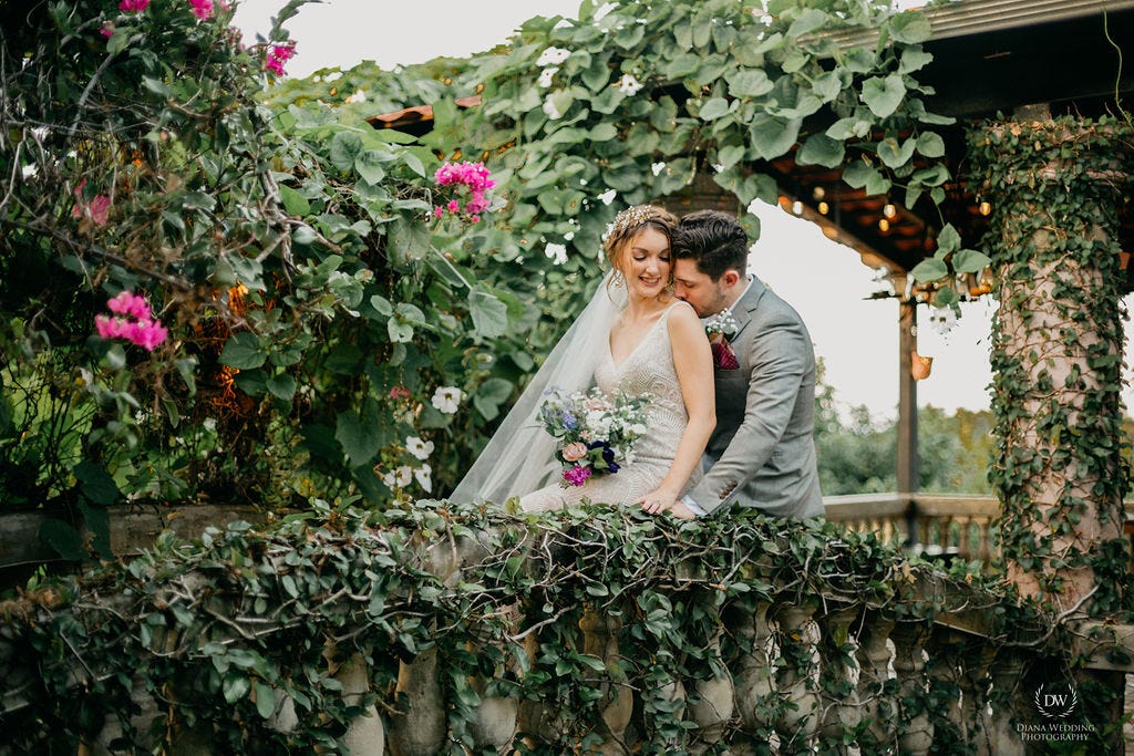 Bride and groom kissing over a bridge