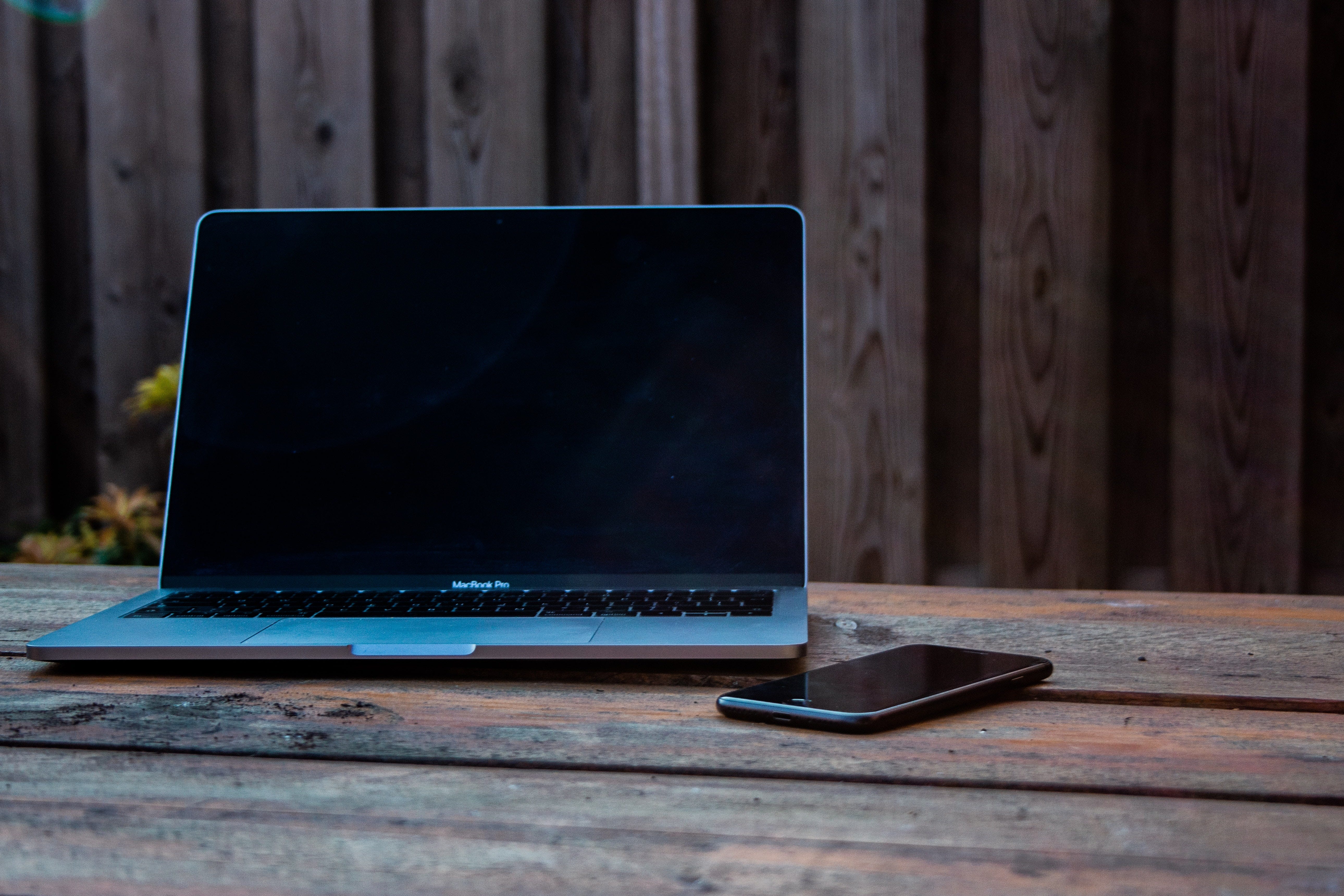 Macbook and Iphone on a worn wooden picnic table