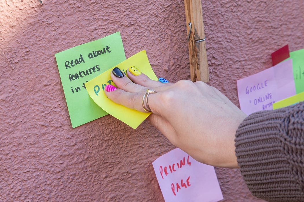 A lady putting up sticky notes on a wall.