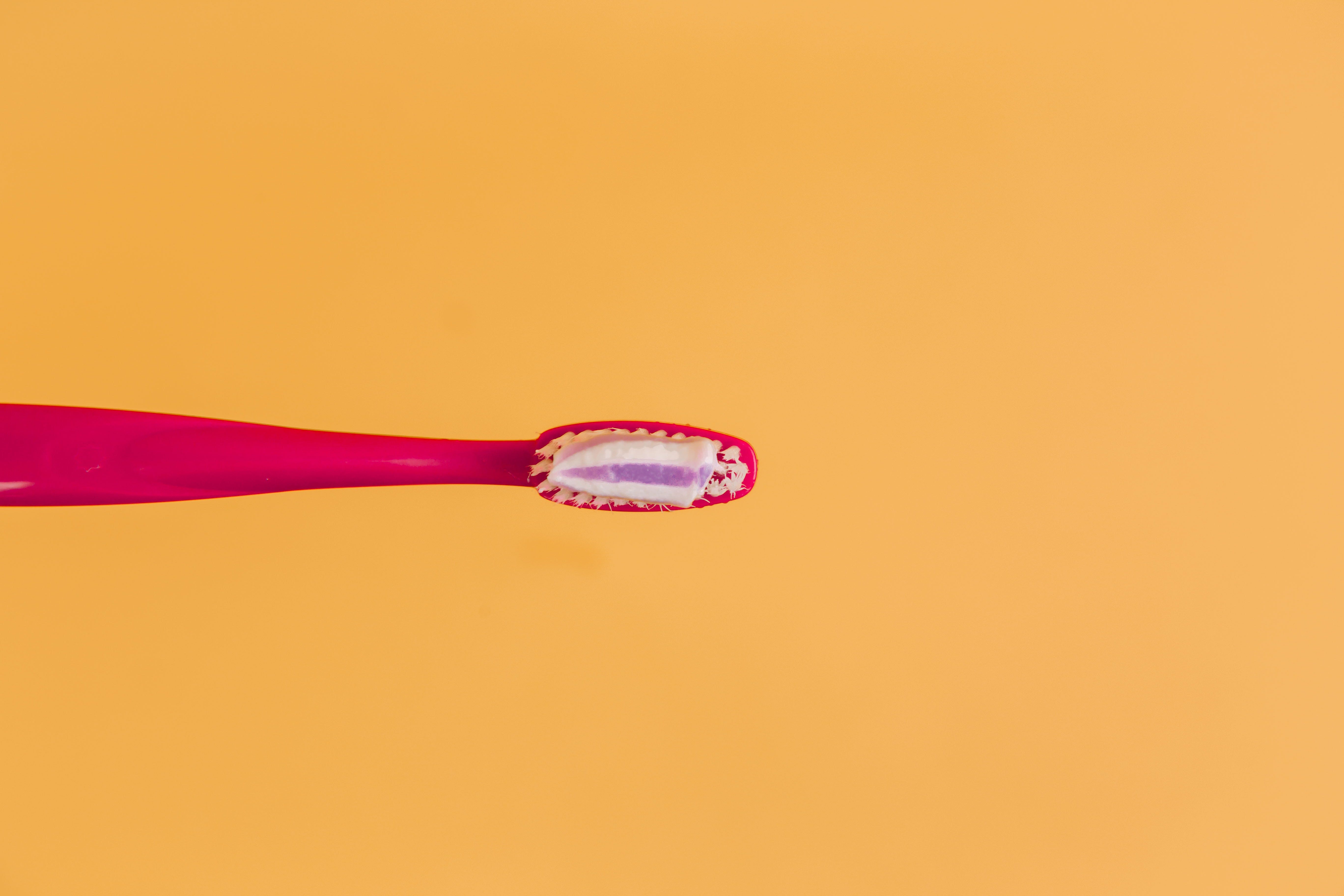 Red toothbrush on contrasting orange background