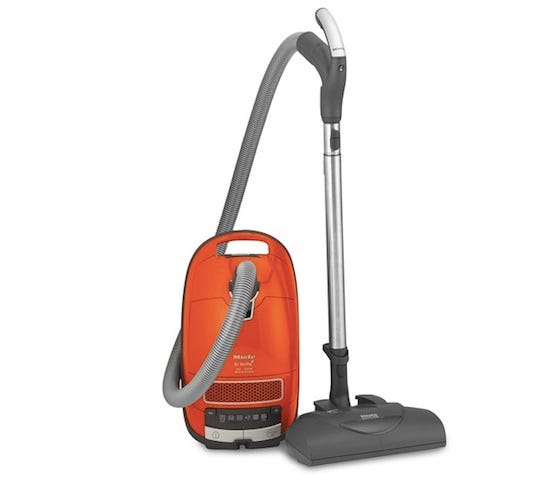A pet hair vacuum featuring an orange tank with a grey hose and silver and grey attachment