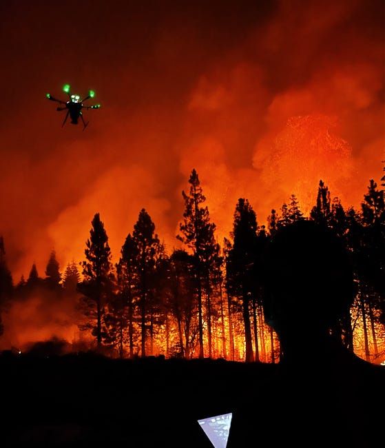 A drone flying over a forest wildfire.