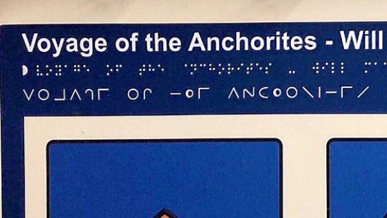 Photo of top of interpretation panel with visual, braille and Moon text of artwork title
