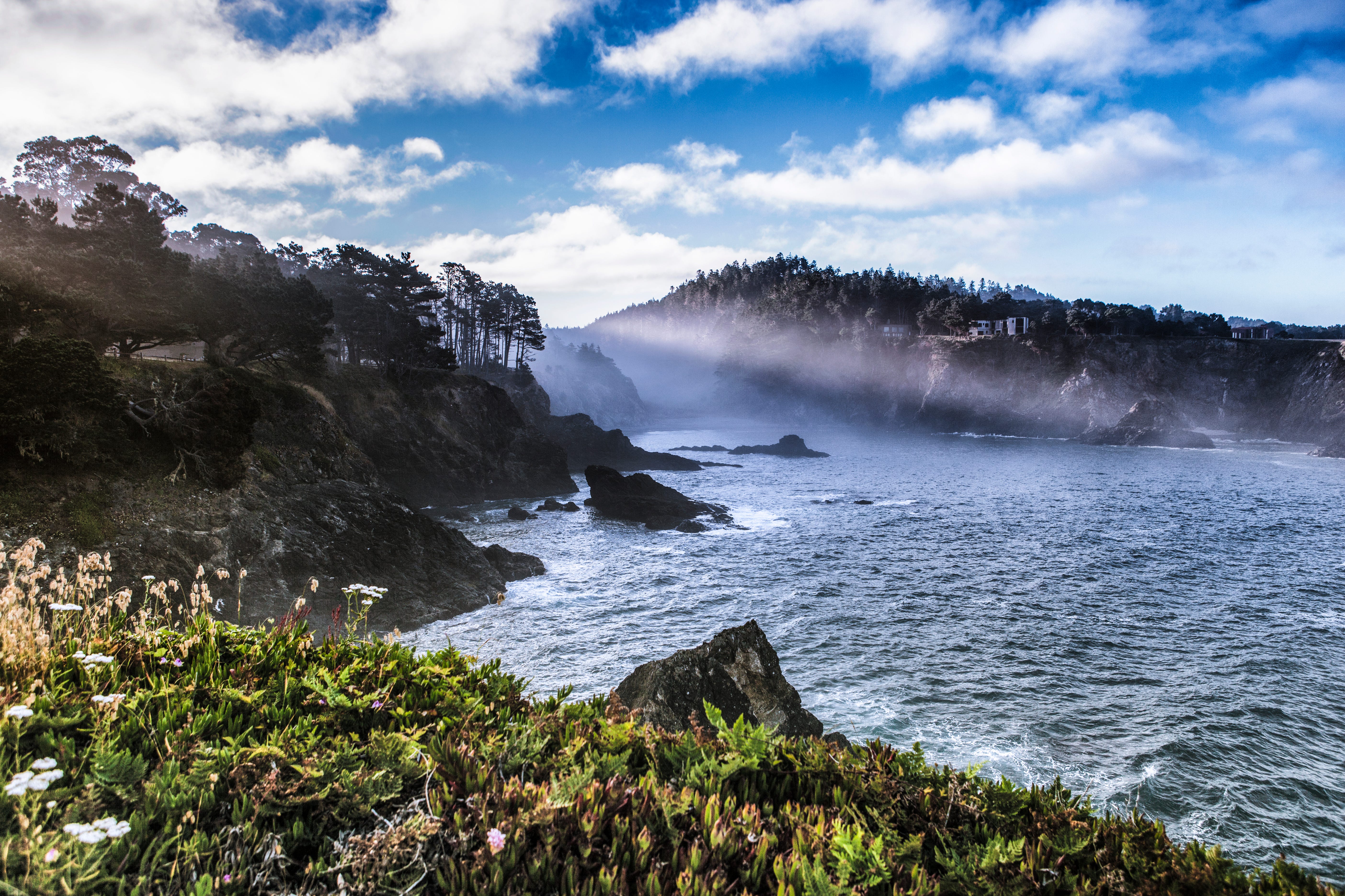 Waves breaking on a rocky coast under a partly cloudy sky.