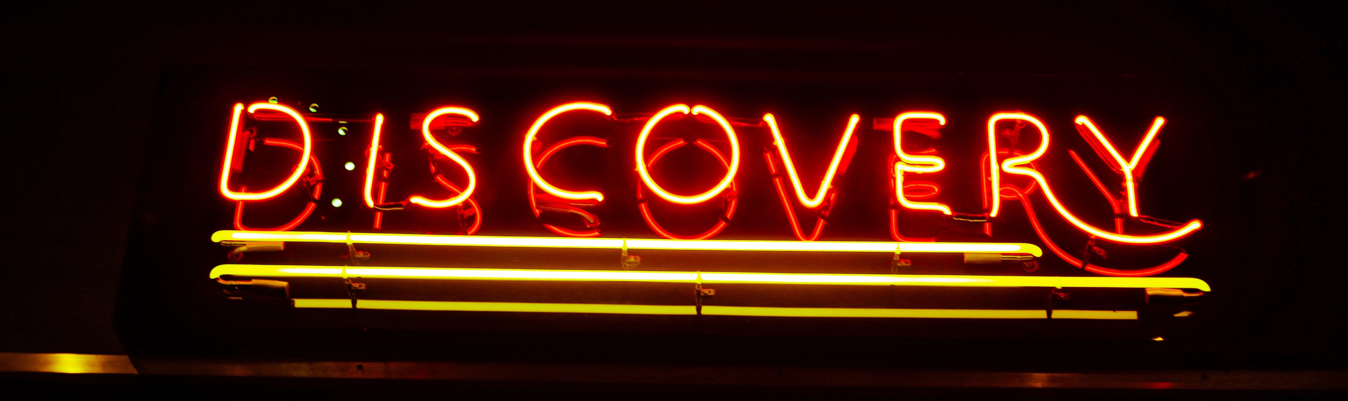 A photo of a neon sign that reads: “Discovery”