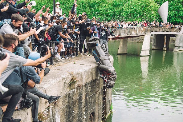 Protestors in Bristol lower a statue into the waters of the dock