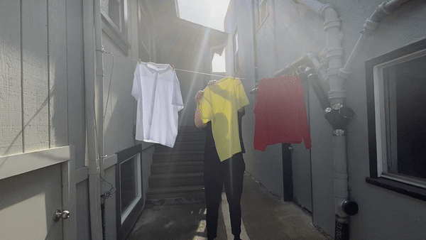 Sunlight shining through a yellow tshirt showing the silhouette of the person hanging it on a laundry line.