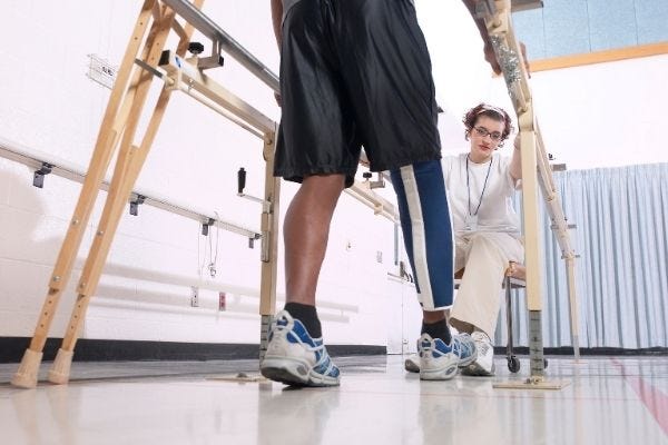 A patient is walking with the assistance of handrails.