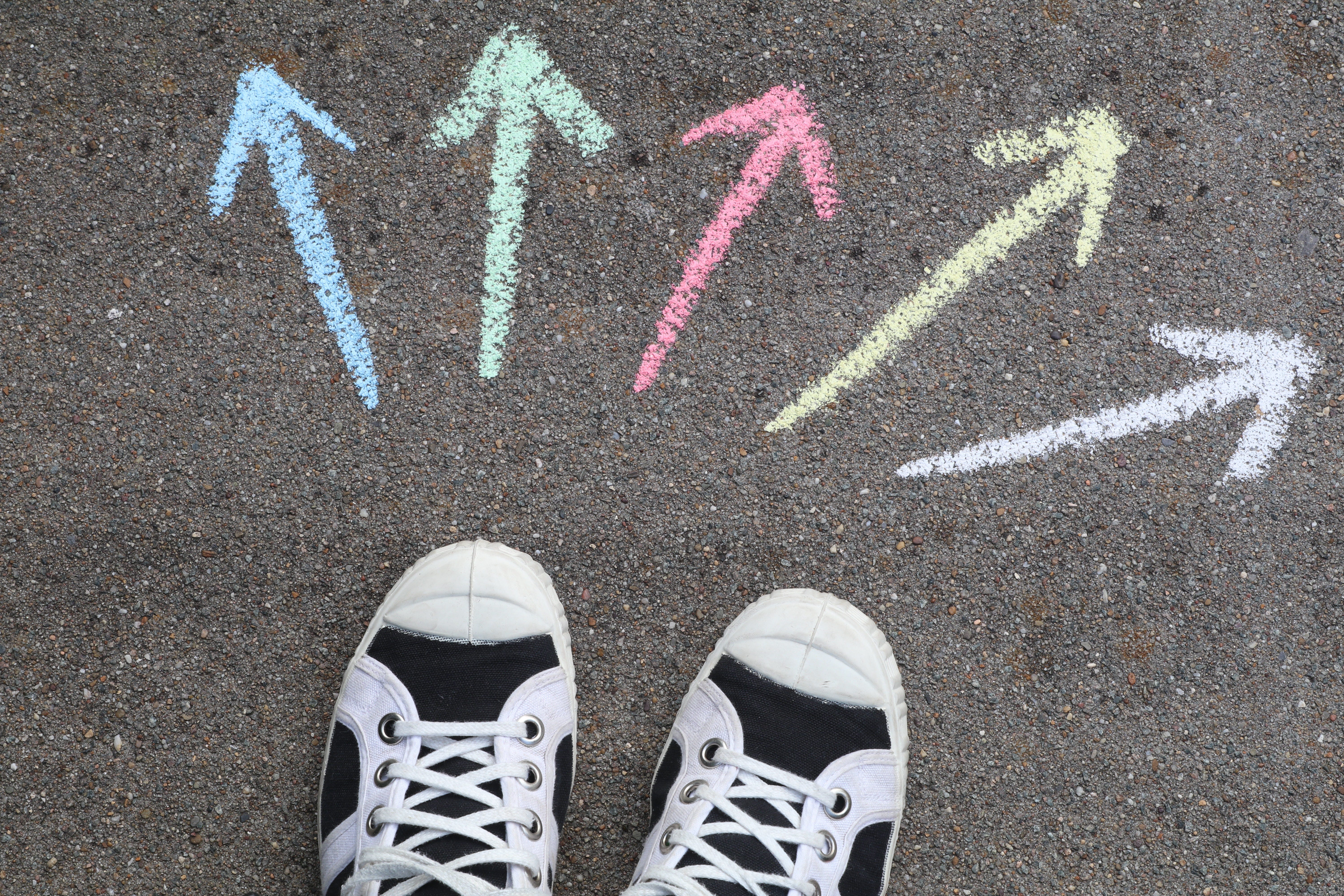 Which way do you go? Arrows pointing 5 different directions in front of sneakers.