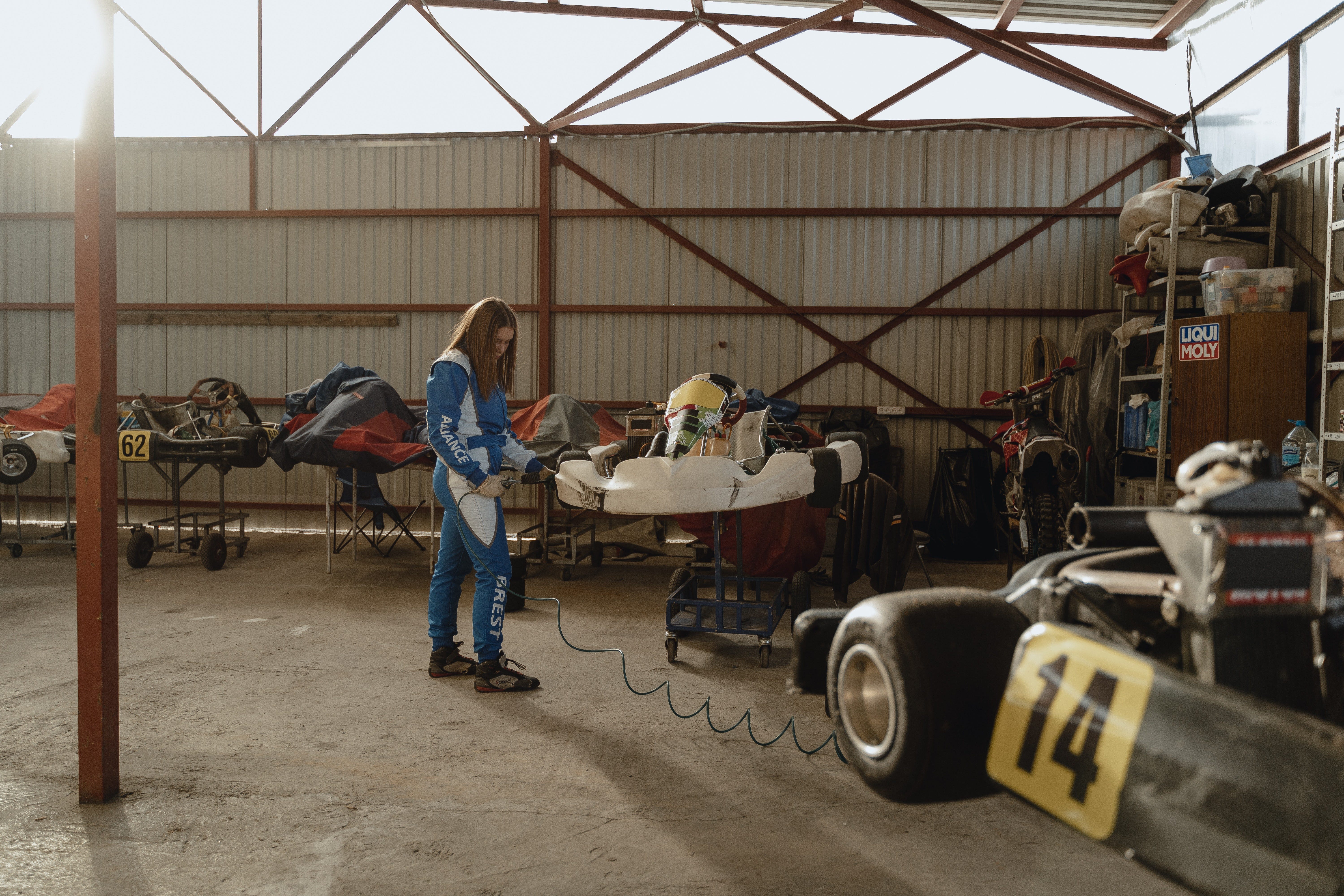 A young racing driver works on her go kart