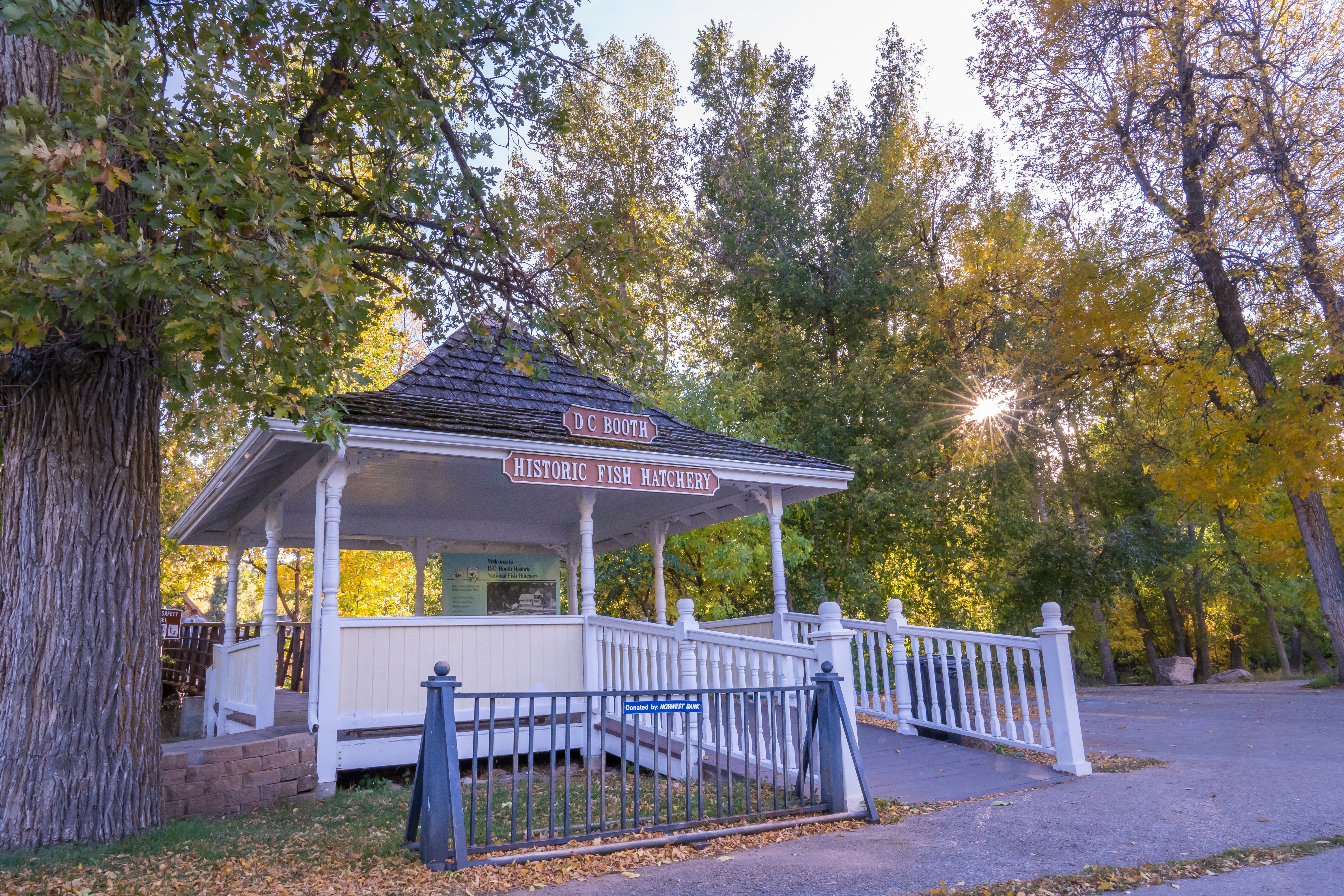 A white gazebo with a sign that says “Historic Fish Hatchery.” Trees with green and gold leaves are in the background.