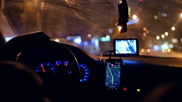 A taxi driver in a car with a routing on his phone to a destination somewhere. It’s already the night and dark inside the car.