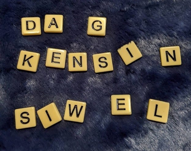 Beige game tiles with black lettering on a dark blue furry blanket display the name DAG … KENSIN… and SIWEL…