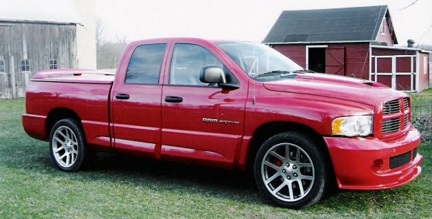 Bright red Dodge Ram SRT-10 parked in front of a red barn.