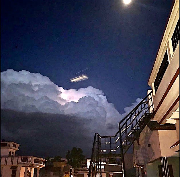 Long spikey UFO light in a cloudy sky above a building at night