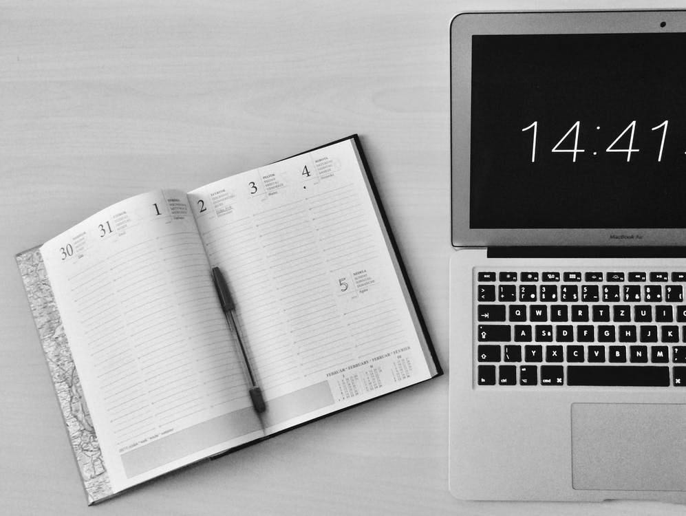 Image of an open planner and the side of a laptop