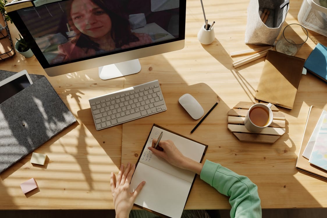 Image of a woman writing notes on top of a cluttered desk