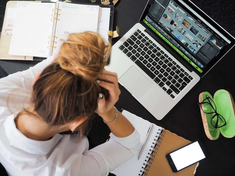 Image of a stessed woman looking at her laptop on a cluttered desk