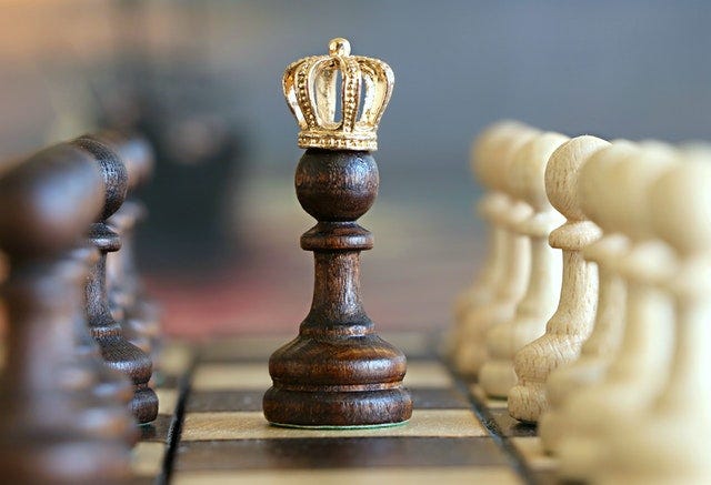 Chess board with a pawn in the center with a crown.