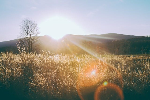 Morning sun lighting a field over the hills