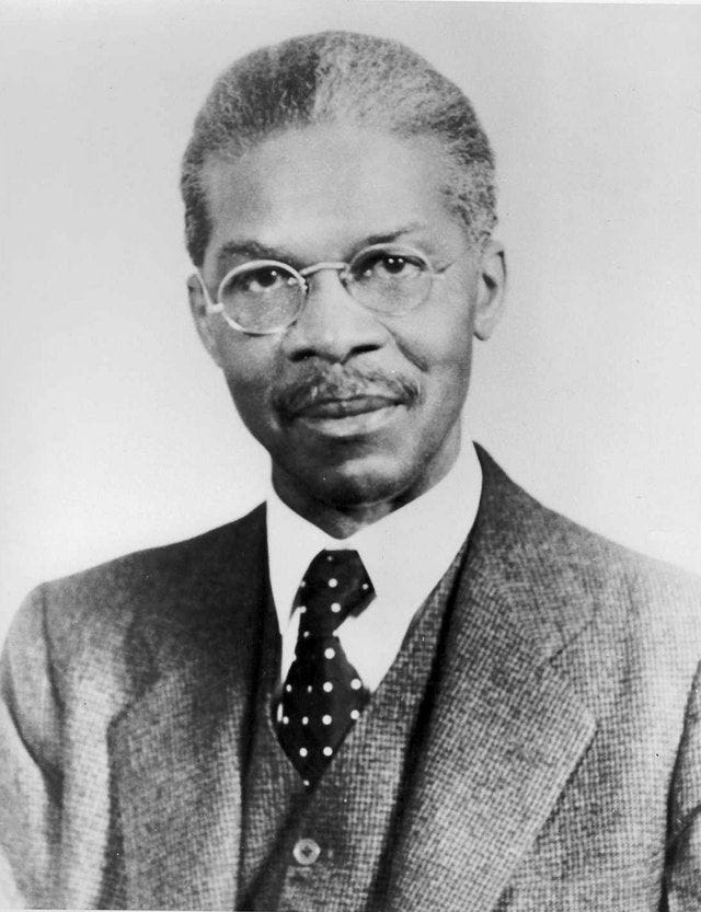 Photo of African American lawyer Louis Gregory, wearing glasses, mustached, wearing suit, white shirt and polka-dot tie.