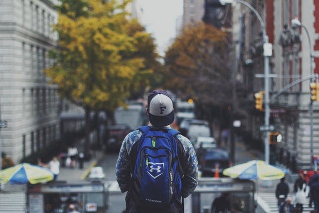 A person stands overlooking a busy street, their back turned to the camera