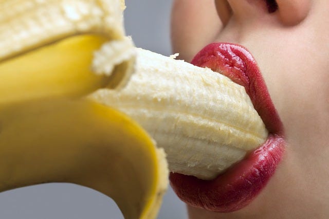 Half-time blow job/by Laura Knapke/medium.com Woman with red lipstick eating a banana.