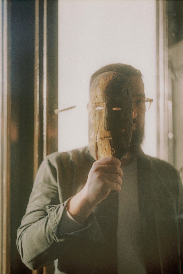 Man’s face is half covered by a wooden mask