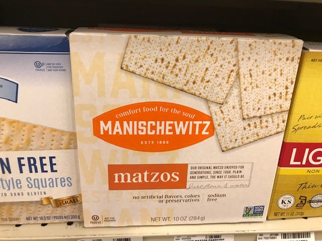 Three boxes of matzo on a grocery store shelf.
