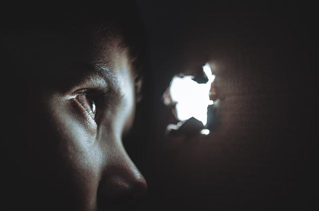 A person peeks through a hole at the light