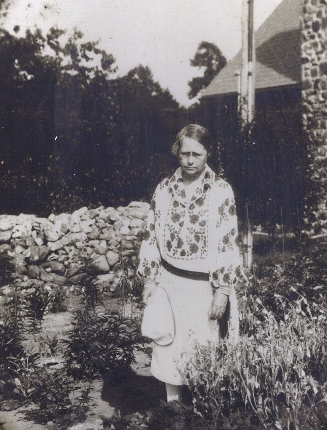a grayscale photo of a woman outside in a garden
