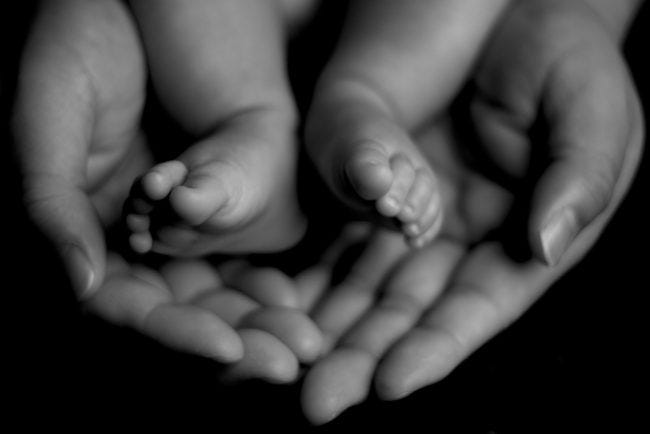 Newborn feet being held by an adults hands.