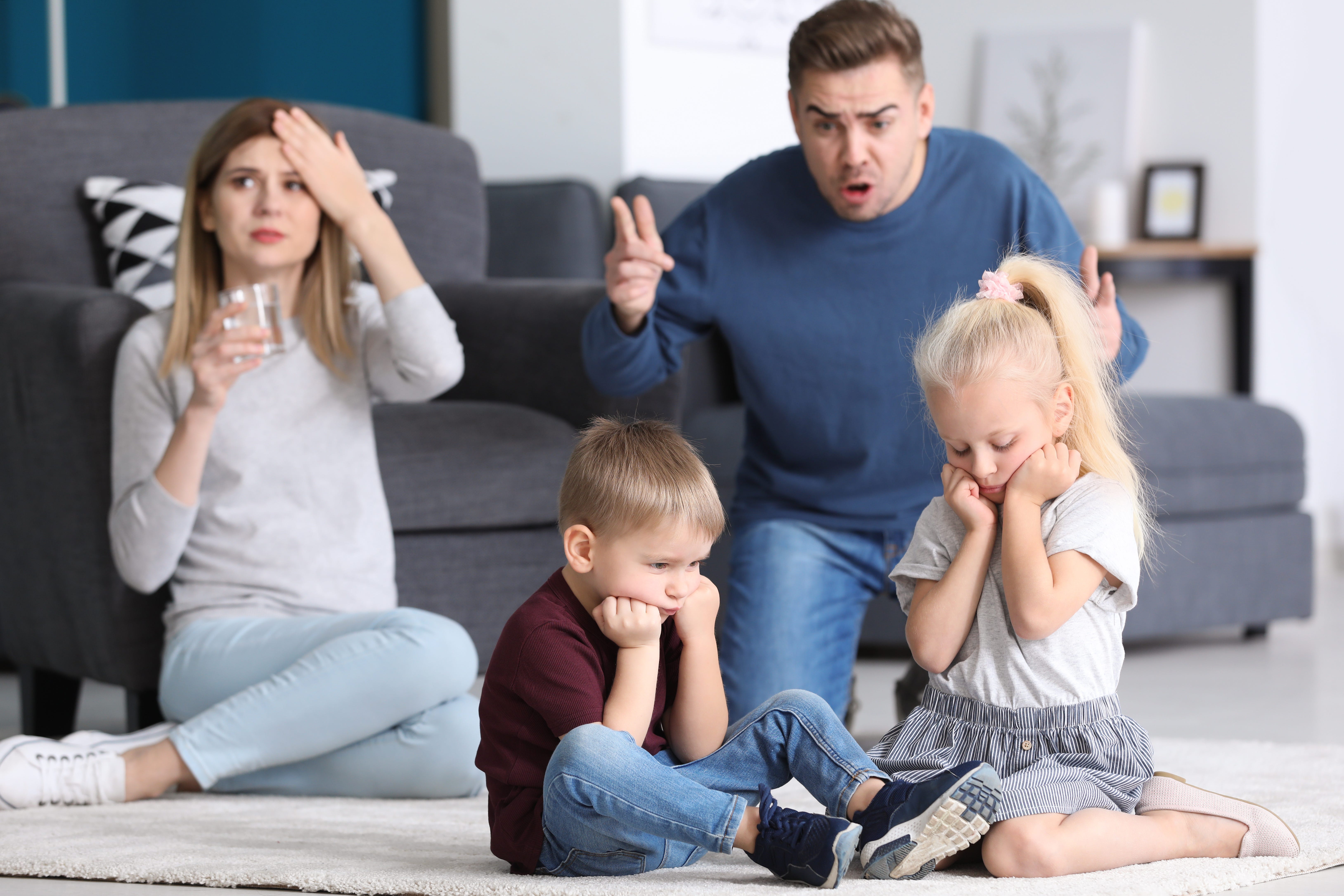 Parents arguing with sad, frustrated children on living room couch