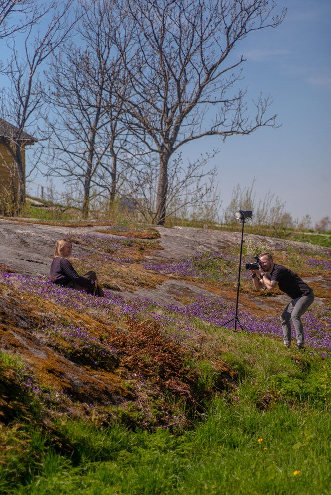 Photographer taking photos of a model in exterior settings, with falsh, in the Helsinki archipelago.