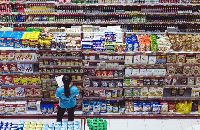 a supermarket employee manually assessing on-shelf availability in a supermarket