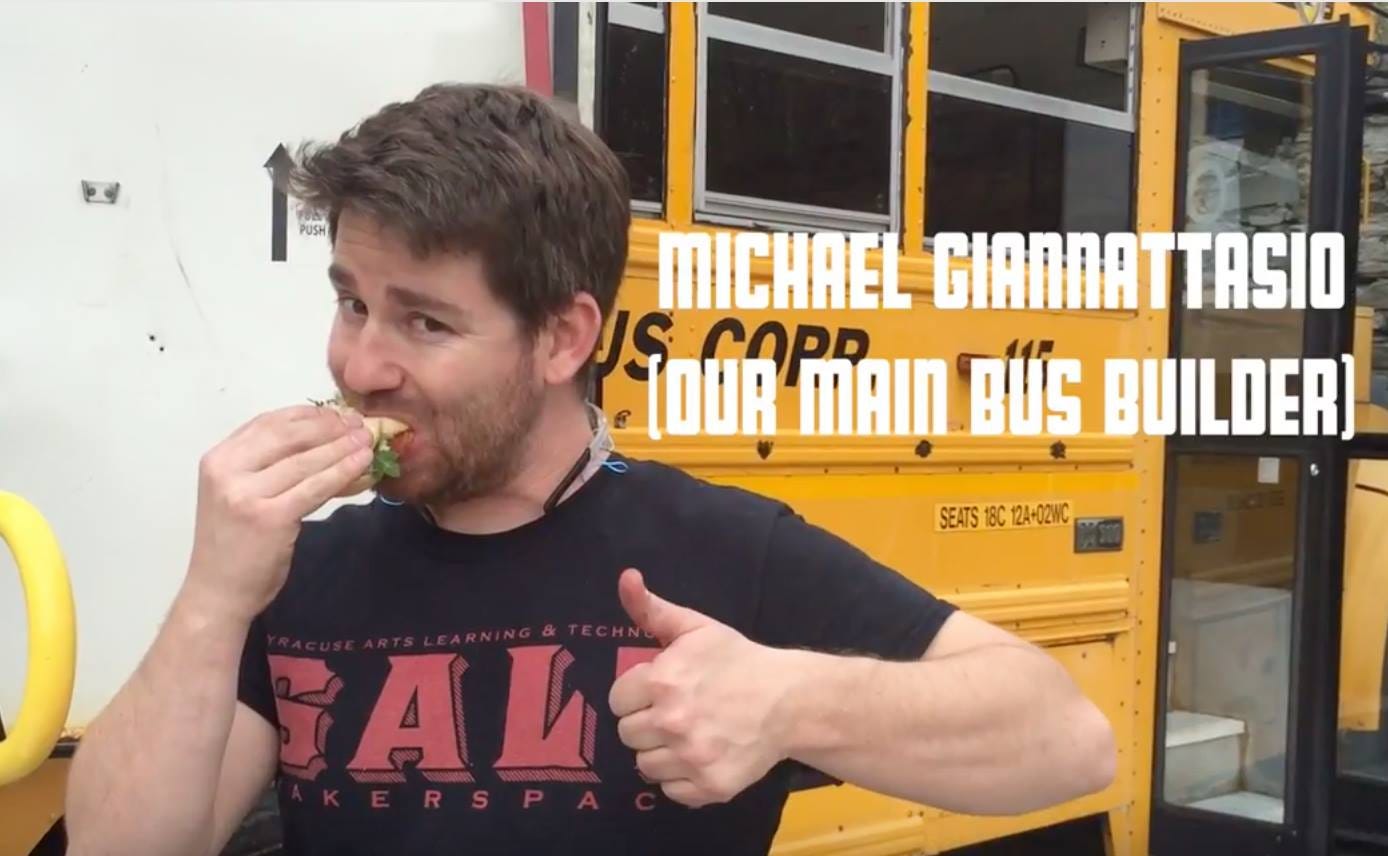 Michael Giannattasio, the main bus builder, eating a sandwich and giving a thumbs up