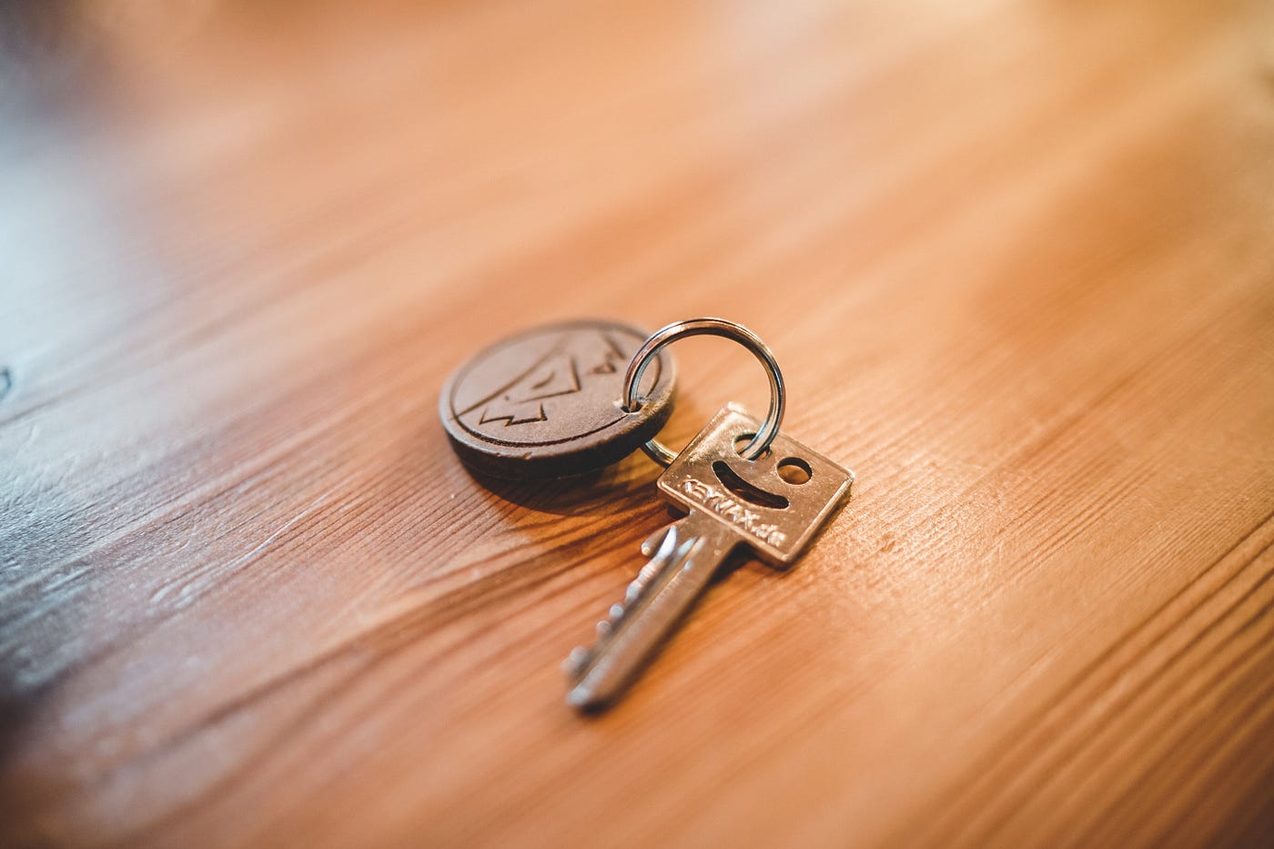 single key with smiley face lying on wooden table; key to freedom