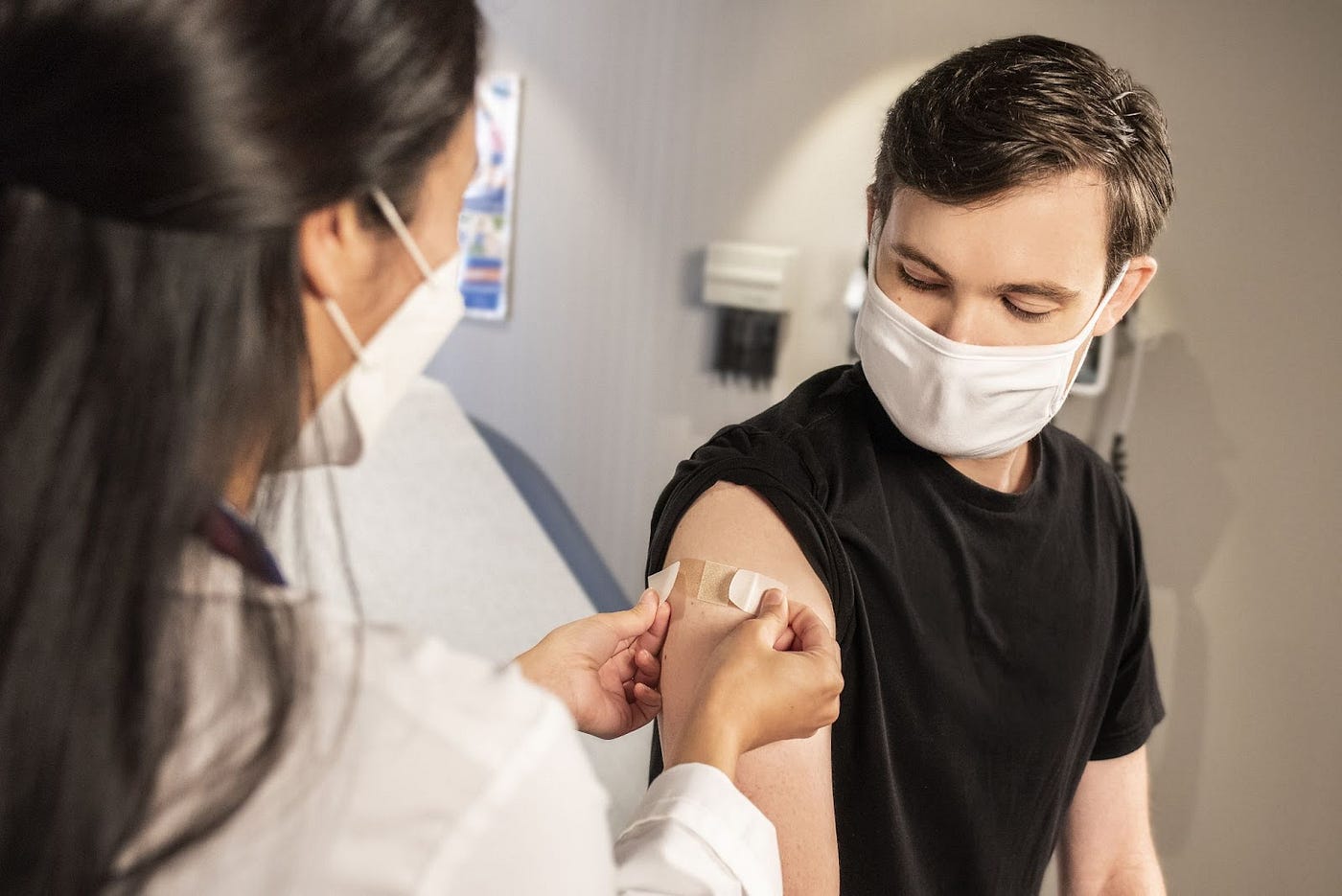 A man getting bandaged in upper arm by a female Doctor.