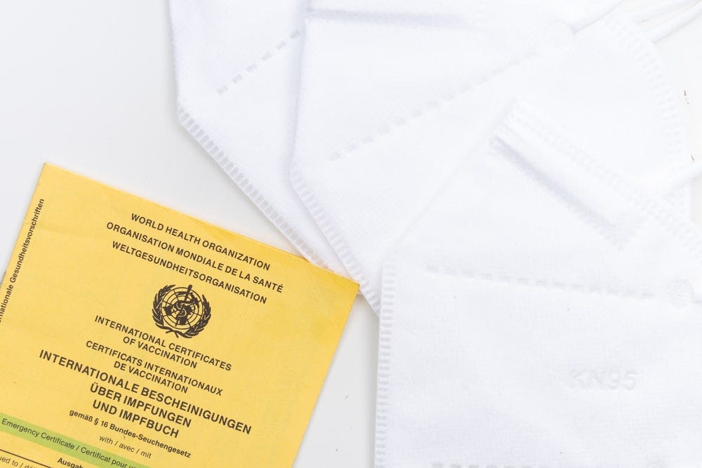 Yellow world health organization vaccination certificate next to a stack of mask filters.