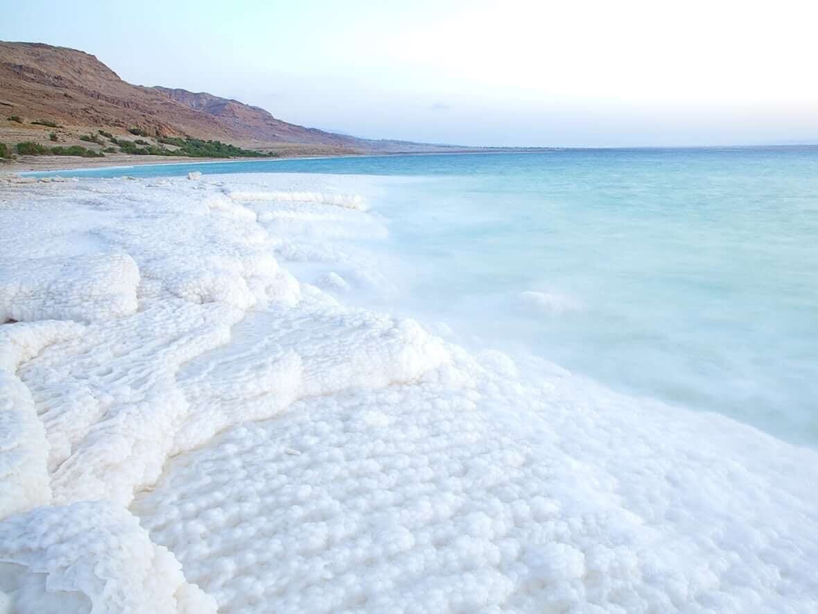 A picture of the dead sea and the white salt deposits forming on its outer edges.