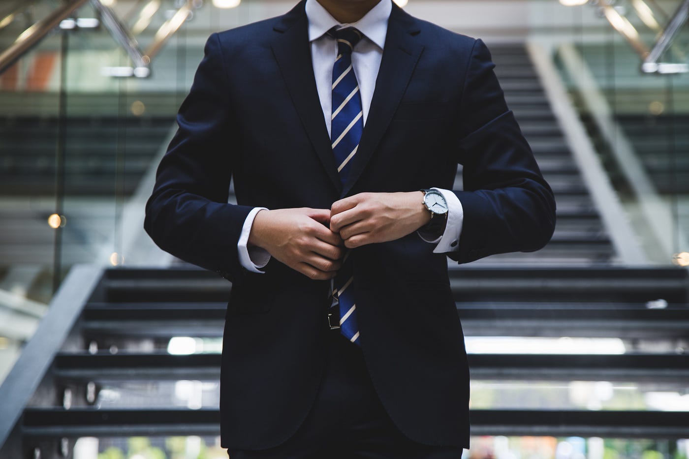 A man buttons his navy blue suit jacket.