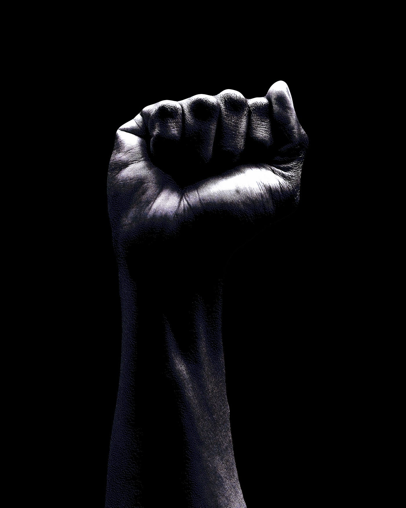 Arm held up, facing us with a closed fist. Black background. Black and white image.