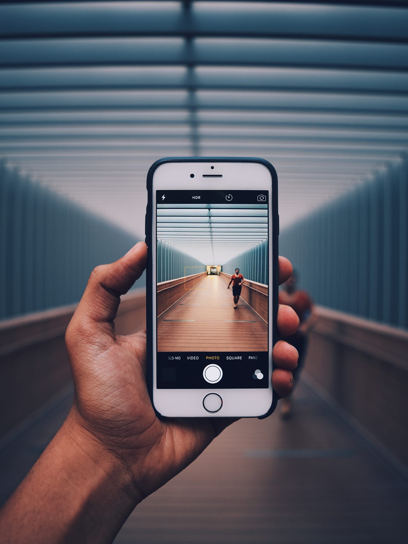 A hand holds up a mobile phone while standing in a work tunnel. We see the tunnel continuing through the screen of the cell phone.