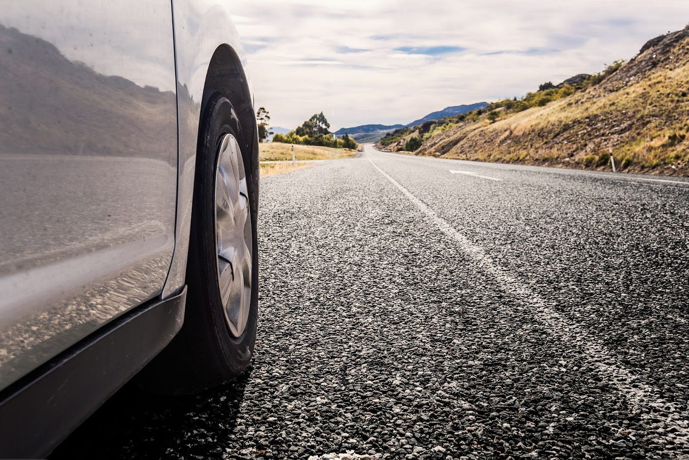 A view of car’s front tire and a road.