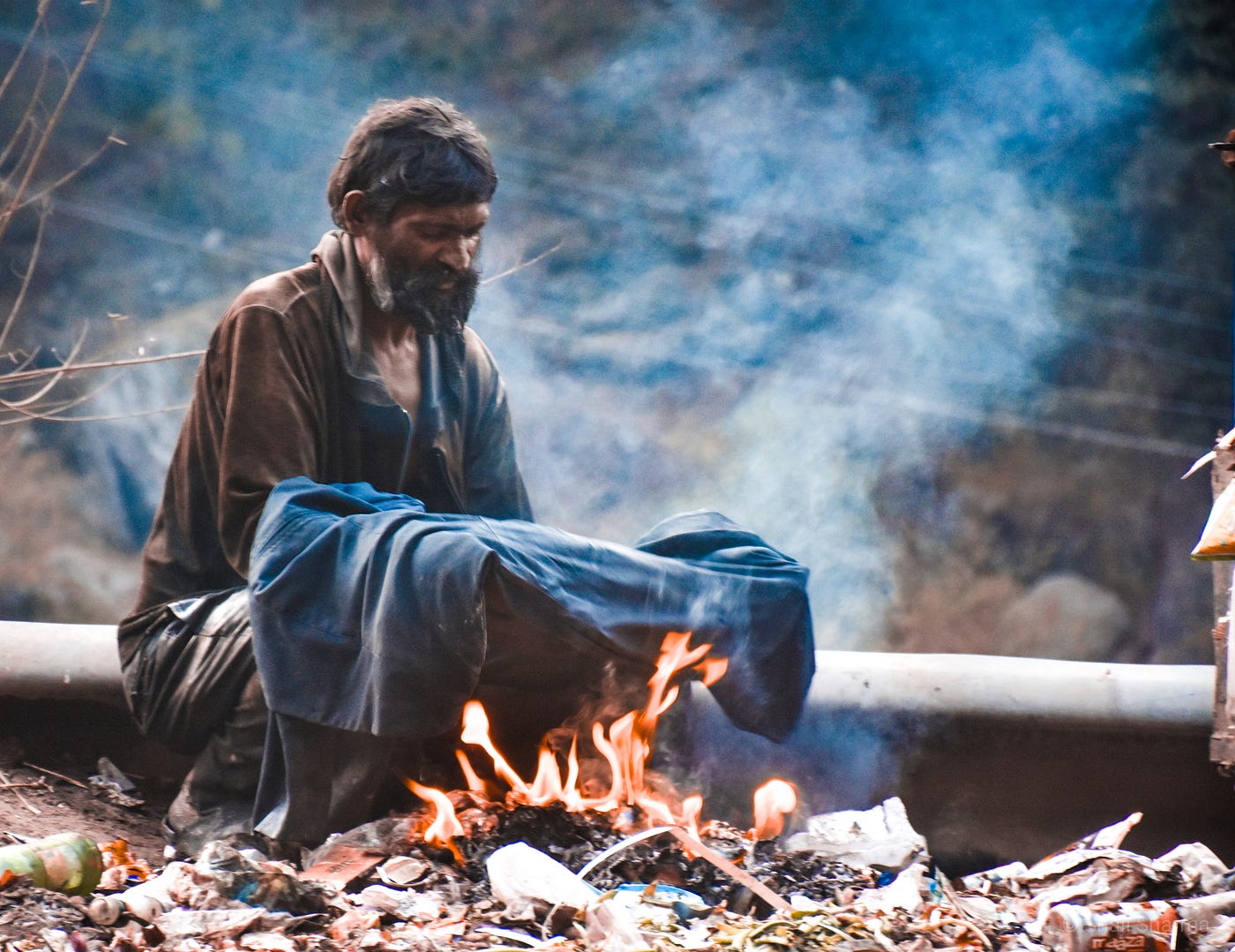 A poor man sitting by a fire.