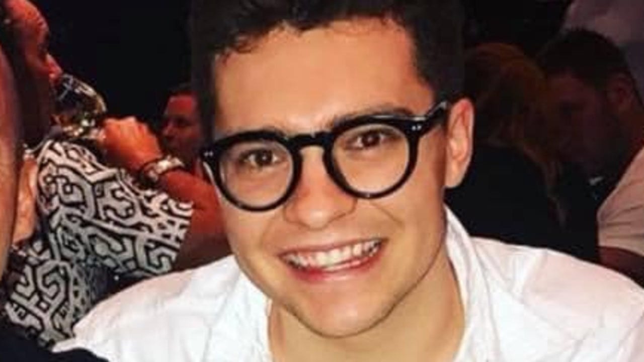 Photo of a smiling Jake Millar wearing his iconic thick-rimmed glasses