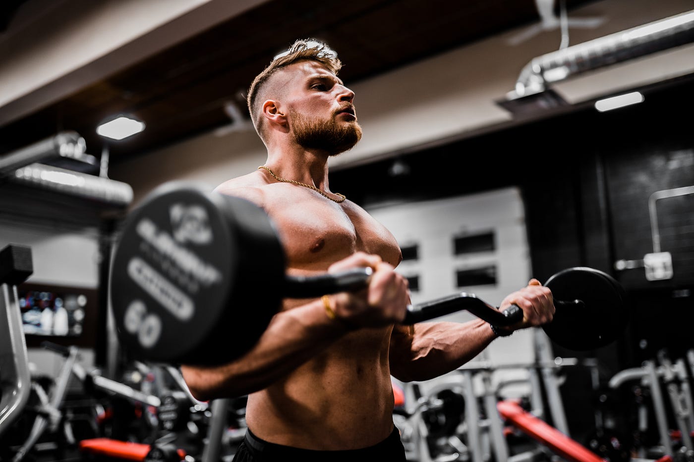 A white male curls a barbell in the gym.