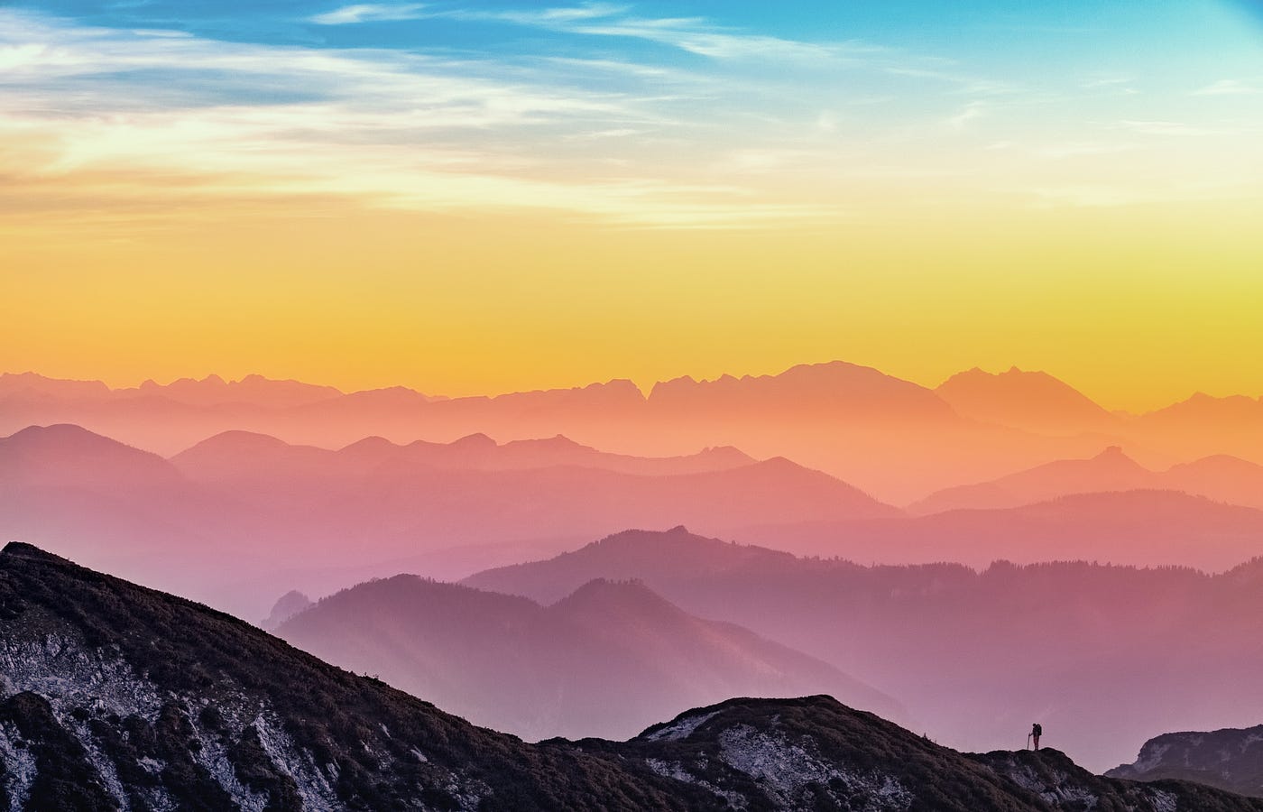 Man on a mountain. Colorful chain of mountains in the background.