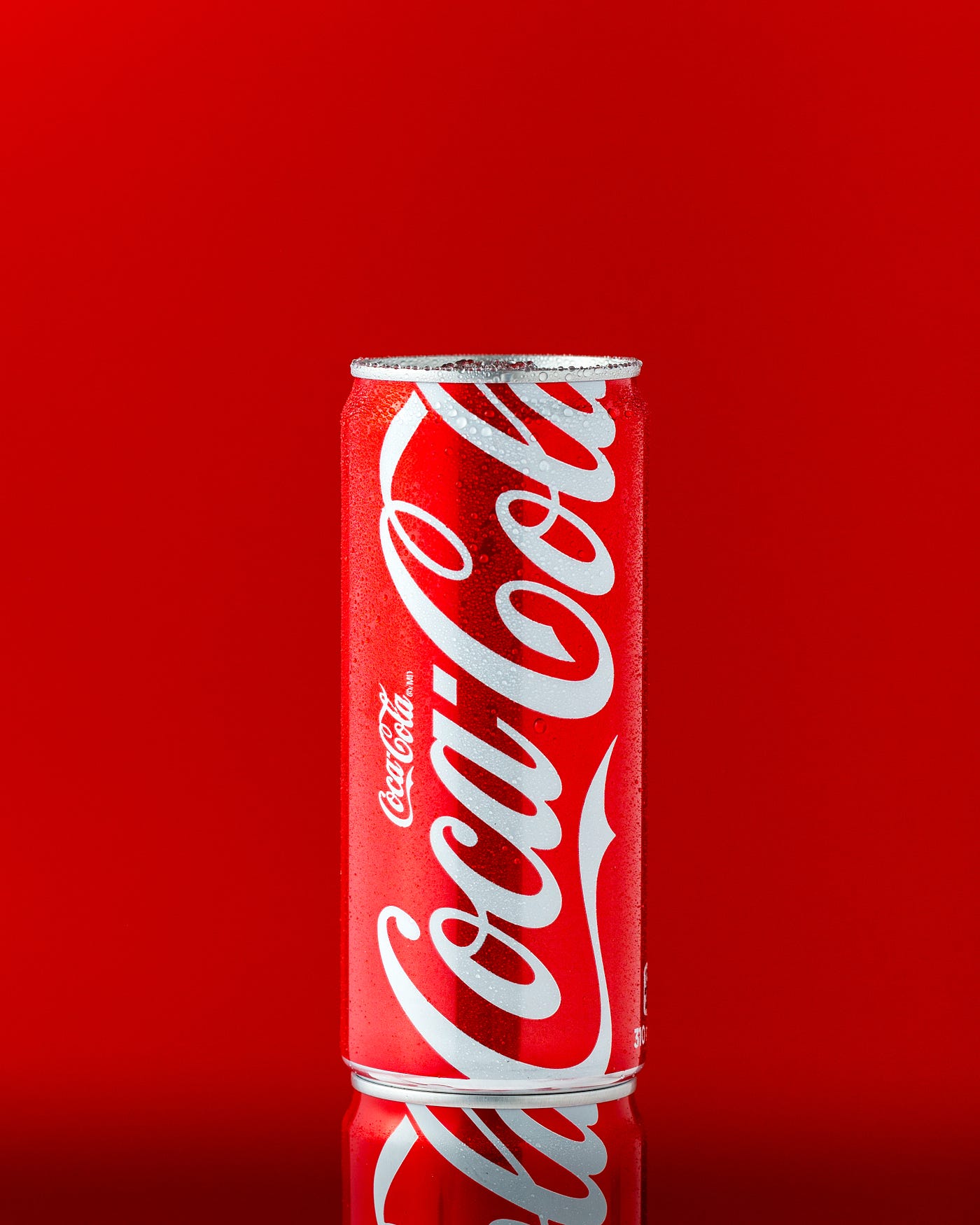 A thin can of Coca-Cola (with the classic lettering) is seen against a red background. Sodas are often full of fructose.